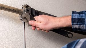 Mechanic works on a high-tension garage door spring
